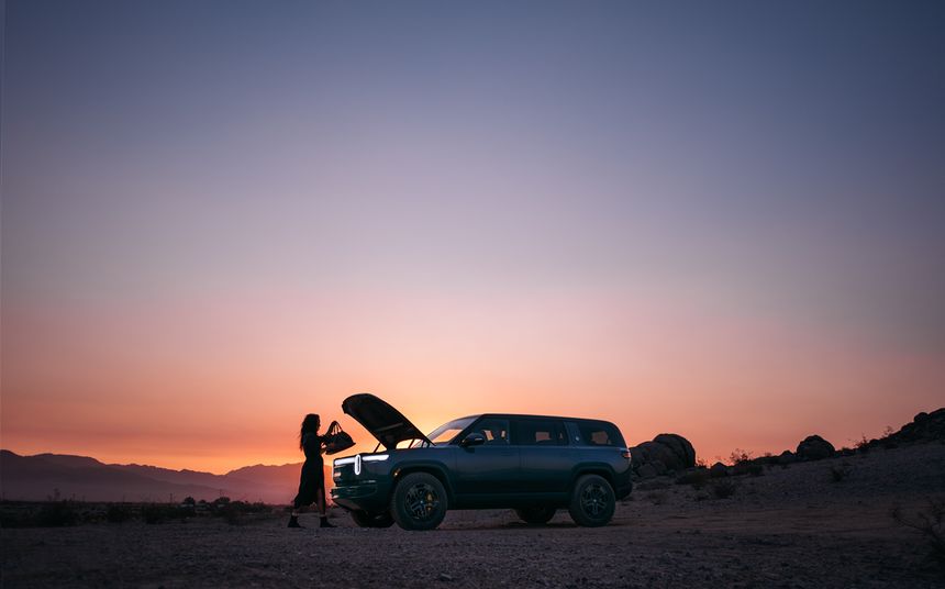 A truck with its hood up in the desert at dusk